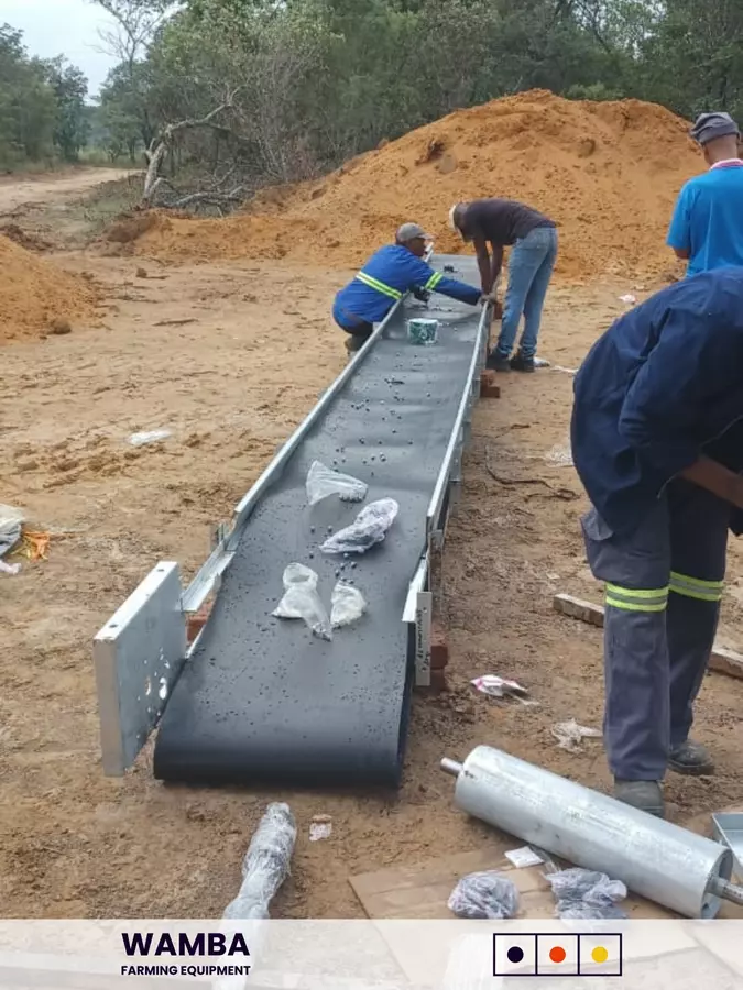 Workers assempling manure conveyor section.